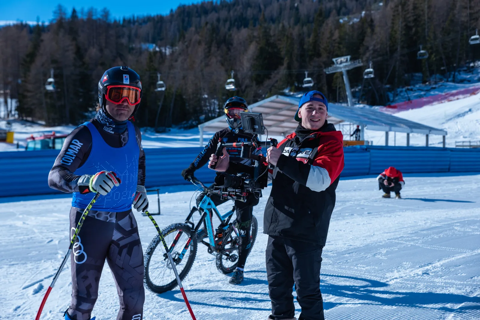Operatore con gimbal accanto a uno sciatore e a un biker in una giornata di riprese in montagna