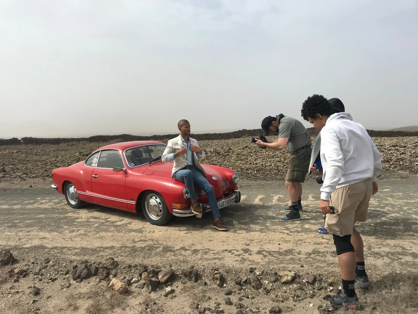 Backstage di uno shooting con auto d'epoca rossa in un paesaggio vulcanico